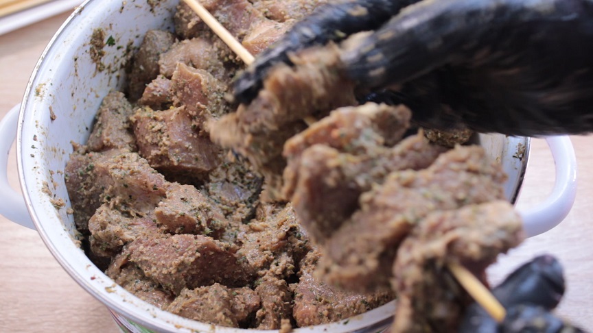 нанизывание мяса на деревянные шампура, сборка шашлыка перед зажариванием